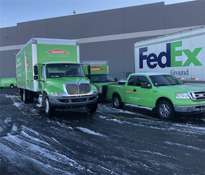 SERVPRO and FedEx trucks sit outside on a lightly snowy road. 